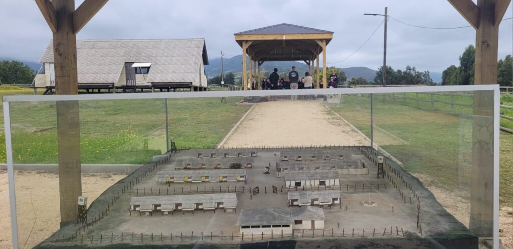 Maqueta del antiguo Campo de Prisioneros Políticos Melinka-Puchuncaví, con la cabaña histórica y el nuevo sombreadero al fondo.